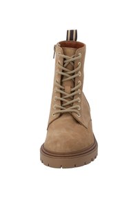 Stivale alla caviglia in suede tan con lacci frontali, punta tonda, suola in gomma marrone e tassello a strisce sul tacco. Texture liscia con dettagli di design minimi.