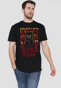 Schwarzes Baumwoll-T-Shirt mit einem grafischen Druck einer Katze und dem Text "Manchmal ist tot besser" in Rot und Gelb. Normale Passform.