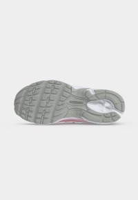 Γκρι λαστιχένια σόλα ενός sneaker New Balance που δείχνει το σχέδιο πέλματος και το λογότυπο σε λευκό φόντο.
