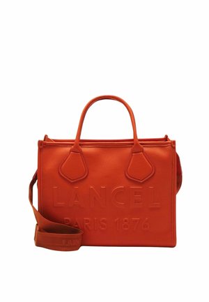 Sac à main en cuir orange avec un logo en relief, forme structurée, deux poignées supérieures et une bandoulière amovible. Texture lisse.