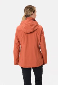 Giacca arancione resistente all'acqua con cappuccio, caratterizzata da una texture liscia e un design aderente. La vista posteriore mostra cuciture seamless e nessun hardware visibile.