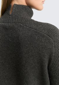Dunkelgrauer Pullover mit hohem Kragen und Rippendetails, strukturiertem Strickstoff und einem seitlichen Schlitz am Hals für zusätzliche Designelemente.