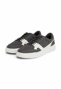 Sneakers in suede grigio con suola in gomma bianca, rivestimento in tessuto, design classico con lacci e un accento bianco a contrasto sul lato.