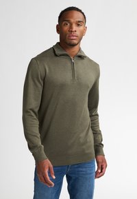 Olijfgroene quarter-zip trui met een textured breisel, geribde manchetten en zoom. De stof lijkt zacht en van gemiddelde dikte, ideaal voor het creëren van lagen.