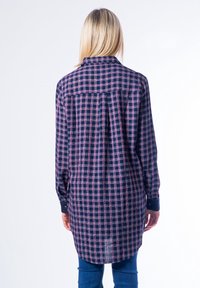 Camicia con maniche lunghe e bottoni di colore blu navy con motivo a quadri rosa e bianco; presenta un colletto, una piega sul retro e un orlo arrotondato.