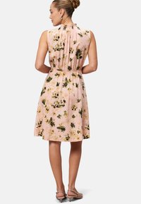 Floral dress in light pink fabric with green and yellow flowers; sleeveless with gathered neckline and elastic waist, above-the-knee length.