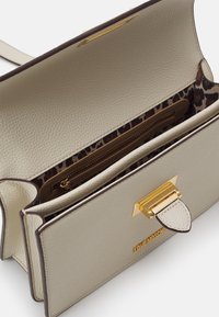 Borsa a tracolla in pelle beige con hardware dorato, foderata internamente con stampa leopardata e tasca con cerniera. Presenta un design strutturato e chiusura a pattina.