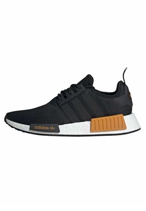 Czarny sneaker Adidas z białą podeszwą, trzema czarnymi paskami po bokach, brązowymi prostokątnymi akcentami i sznurowanym zapięciem.
