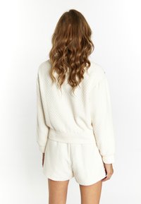 Weißes strukturiertes Strick-Sweatshirt und Shorts-Set mit lockerer Passform, kurzem Design und elastischem Bund für zusätzlichen Komfort.