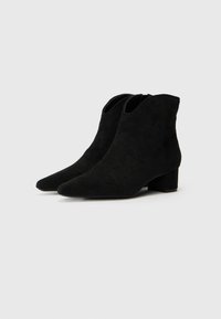 Bottes de cheville en daim noir avec un bout pointu et un talon bloc moyen. Présente un design découpé sur les côtés pour faciliter l'enfilage.