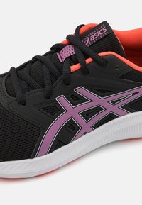 Botte de sport noire avec tige en mesh, accents violets et semelle intermédiaire blanche. Le design comprend des lacets noirs et un intérieur rose corail lumineux.