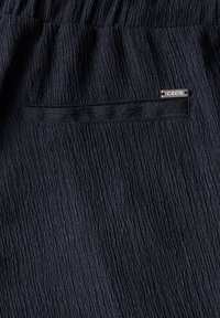 Navy textiel met een gekreukt ontwerp, voorzien van een klein metalen label met de inscriptie "CECIL". Inclusief een discrete achterzak.