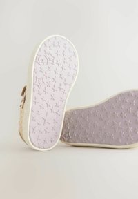 Chaussures pour enfants avec des semelles en caoutchouc rose texturé. Les semelles présentent un motif d'étoiles, entouré d'un bord de couleur claire.