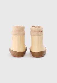 Korte beige gummistøvler med en teksturert brun såle og en samlet stoffkant på toppen. Glatt overflate og rund tådesign.