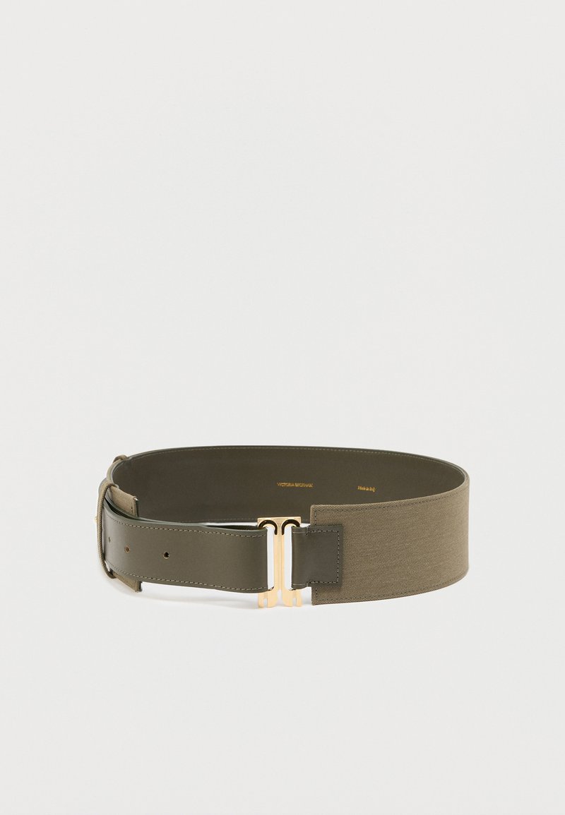 Ζώνη ελιάς με λείο φινίρισμα δέρματος, που διαθέτει αγκράφα σε χρυσό τόνο και υφασμάτινη υφή. Το πλάτος είναι ομοιόμορφο με πολλαπλές τρύπες.