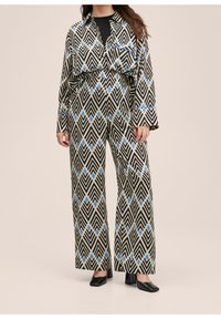 Mono estampado en negro y beige con formas geométricas de diamante en azul, mangas largas, cuello y un corte holgado.