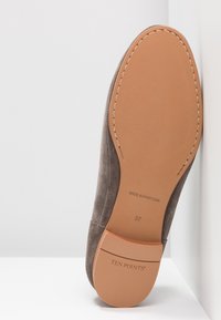 Semelle de chaussure en daim marron avec un dessous en caoutchouc lisse couleur tan. Présente des surpiqûres sur les côtés et un marquage gravé. Taille indiquée comme 37.