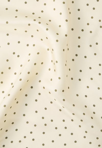 Ύφασμα κρεμ με μικρές πουά σε λαδί πράσινο, ομοιόμορφα κατανεμημένες, παρουσιάζοντας απαλά πτυχώσεις και υφή.