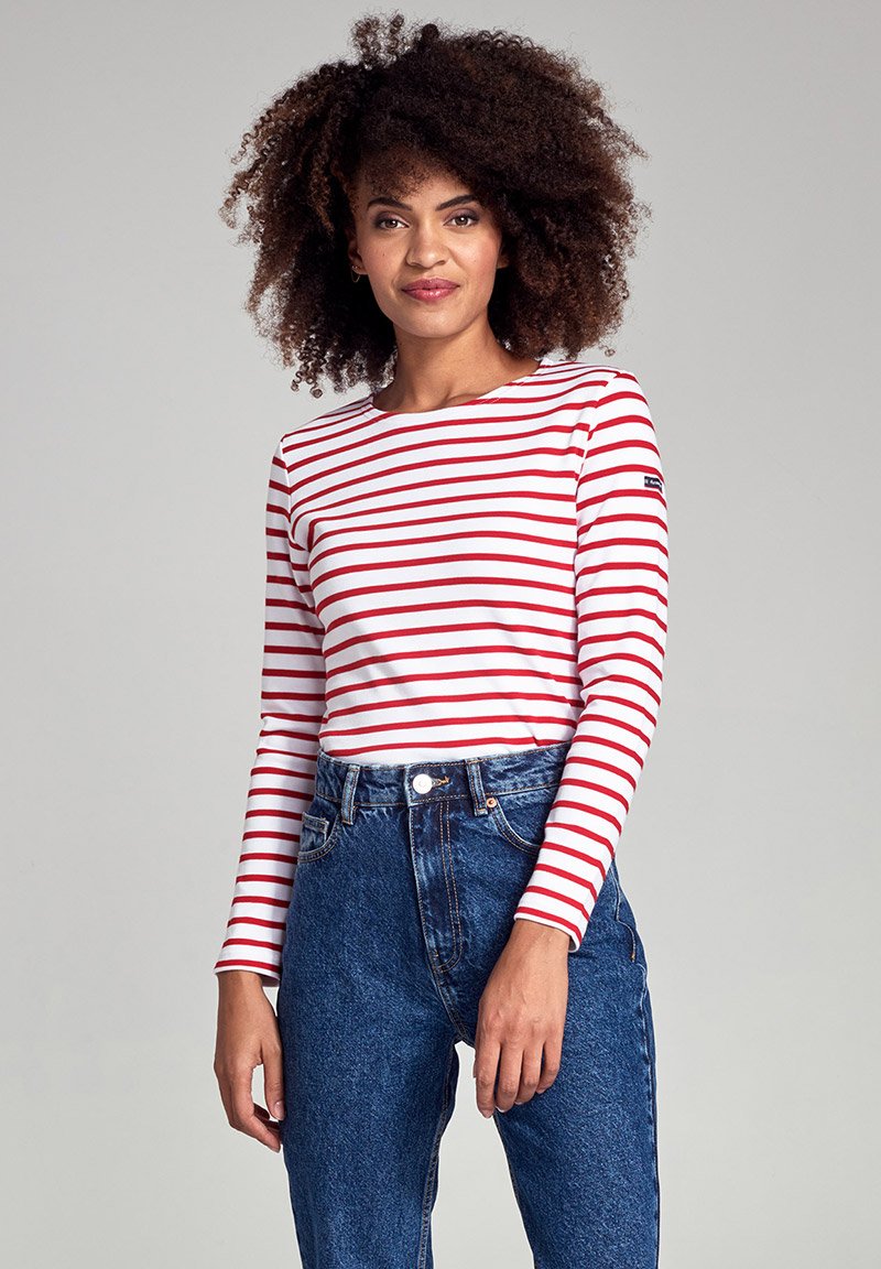 T-shirt à manches longues avec des rayures horizontales rouges et blanches, en coton. Associé à un jean en denim bleu taille haute, mettant en valeur une coupe classique.