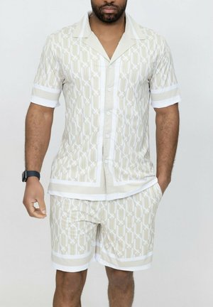 Chemise à manches courtes à motifs beige clair avec des accents blancs ; le short assorti présente le même design. Le tissu semble lisse et léger.
