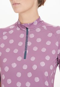 Lila Sporttop mit einem halben Reißverschlusskragen und weißen Punktmustern, aus einem glatten, dehnbaren Stoff gefertigt. "ENDURANCE"-Logo am Reißverschluss.
