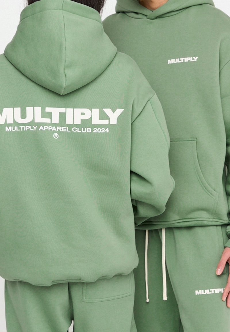 Felpe verde realizzate in morbido tessuto, con grande testo bianco sul retro. Include una tasca a marsupio e dettagli con stringhe sulla cappuccio.