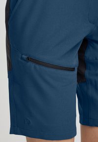 Shorts pour hommes en tissu bleu profond avec une texture lisse. Comprend une poche latérale avec une fermeture éclair noire et un panneau noir sur le côté.