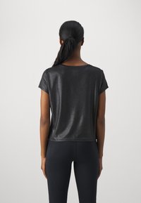 Camiseta metálica negra de manga corta, con un corte holgado y un escote redondo, textura suave y un ligero brillo. Largo ligeramente recortado.