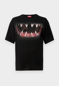 Black Diesel t-shirt with graphic of sharp white teeth and dark rocky shapes on front, folded sleeves, red logo tag inside collar.