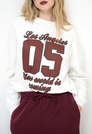 Felpa bianca con grafica borgogna con le scritte "Los Angeles" e "05", abbinata a pantaloni jogger borgogna con vita elasticizzata.