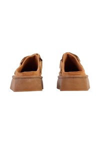 Paire de chaussures en daim beige à enfiler avec semelles en caoutchouc épaisses, vues de dos sur un fond blanc.