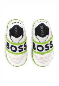 Witte sportieve schoenen met groene accenten, mesh materiaal en een brede band met "BOSS" in donkere letters over de bovenkant.