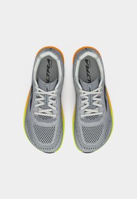 Ζευγάρι γκρι αναπνεύσιμων αθλητικών παπουτσιών με λευκά κορδόνια και σόλες με διαβάθμιση από πορτοκαλί σε κίτρινο, σε θέα από πάνω σε λευκό φόντο.