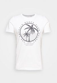Camiseta de algodón blanca con un diseño gráfico redondo que presenta palmeras y el texto "Emerald Beach Club Resort" en negro.