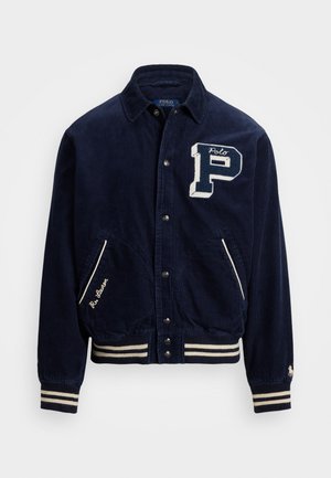 Navy Blau Cordjacke mit weißen gestickten "P" und "Polo" Details, Knopfverschluss vorne, zwei Seitentaschen sowie gestreiften Rippbündchen und Saum.