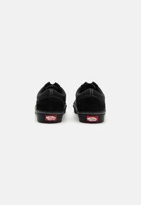 Sorte sneakers med overdel i semsket skinn og kanvas, hvite sømmer og rødt logo på hælen. Rund tå og flat gummisåle. Enkelt design.