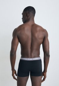 Sorte boksershorts med en grå midjebånd som har "KARL LAGERFELD" logo. Materialet virker glatt, med en tettsittende passform.