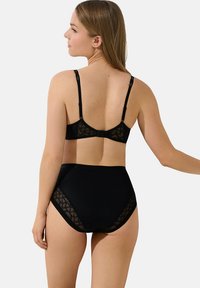 Ensemble de lingerie noire comprenant un soutien-gorge avec des bretelles réglables et une culotte taille haute. Les deux pièces présentent des accents géométriques transparents.