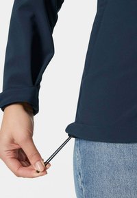 Marineblaue Jacke mit glatter Textur. Eine Hand zieht eine verstellbare Kordel aus dem Saum, die schwarze Beschläge und subtile Nähdetails aufweist.