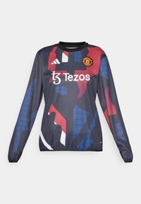 Langermet sportstrøye i m�ørk marineblå med abstrakte røde og blå mønstre, med Manchester United-logoet og "Tezos" merkevare på fronten.