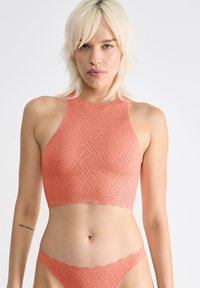Koral crop top med et struktureret mønster, bølgede kanter og høj hals, parret med matchende lavtaljede bikini bukser.