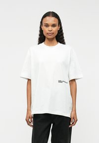 Λευκό βαμβακερό μπλουζάκι με χαλαρή εφαρμογή, στρογγυλή λαιμόκοψη και κοντά μανίκια. Διαθέτει το λογότυπο «KARL LAGERFELD JEANS» σε μαύρο χρώμα στη αριστερή πλευρά.