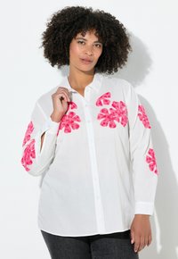 Weißes Hemd mit knöpfen und rosa Blumenmustern an den Ärmeln. Verfügt über einen Kragen, lange Ärmel und einen lockeren Schnitt mit glatter Textur.