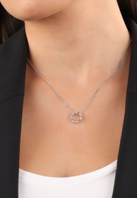 Collana in argento con un pendente circolare adornato da pietre multicolori, che presenta una finitura liscia e un design elegante.