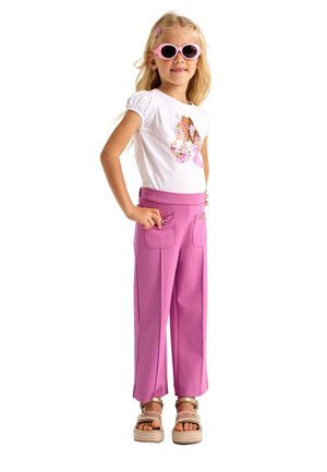 Camicia bianca a maniche corte con grafica colorata, pantaloni rosa a gamba larga con tasche frontali e occhiali da sole rosa chiaro. Sandali espadrille completano l'outfit.