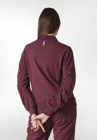 Marin sweatshirt med hög krage och puffärmar. Tillverkad av mjukt material med en texturerad yta och en liten märkesetikett på baksidan.