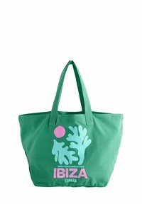 Groene katoenen totebag met twee handvatten, voorzien van een groot blauw koraalontwerp en een roze cirkel, en de tekst "IBIZA" in vetgedrukte roze lettertype.