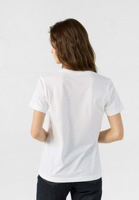 T-shirt bianca a maniche corte con collo rotondo, realizzata in tessuto morbido. La vista posteriore mostra una texture liscia e una vestibilità regolare.