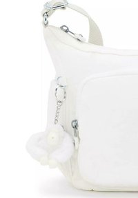 White fabric bag with a smooth texture, featuring a front pocket, silver hardware, and a fluffy white charm attached to a chain.