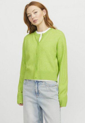 Grüne, gekürzte Strickjacke aus weichem Knit-Stoff, mit rundem Ausschnitt, Knopfverschluss und gerippten Bündchen und Saum. Kombiniert mit hellen Jeans.